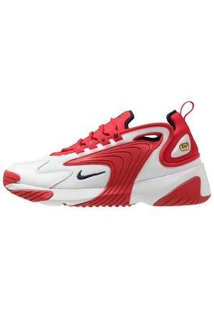 Rode en witte sportschoen van mesh en synthetische materialen, met een gebogen ontwerp, opvallende rode accenten, logodetail en een gestructureerde zool.