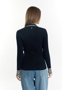 Maglione a coste navy con vestibilità slim, dotato di colletto e polsini a righe bianche. Tessuto testurizzato e dettaglio logo discreto sulla schiena.