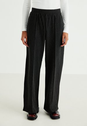 Black, wide-leg pants featuring vertical white pinstripes. Made of a lightweight material with an elastic waistband for comfort.