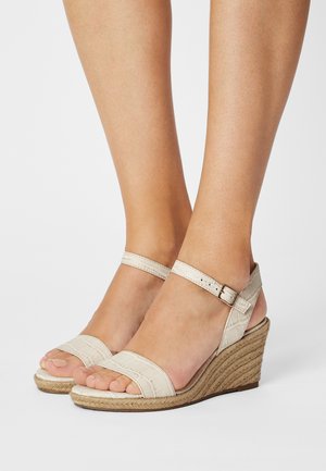 Sandales compensées beiges avec un dessus texturé à motif crocodile, une bride de cheville avec une boucle et une semelle en jute tissé. Design à bout ouvert.