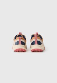 Une paire de chaussures de trail de couleur beige, marine et rose, vue de l'arrière, sur un fond blanc uni.