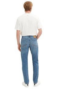 Jeans din denim de culoare albastru deschis, cu croială dreaptă, buzunare dorsale cu detalii de cusătură și o etichetă din piele maro la talie.
