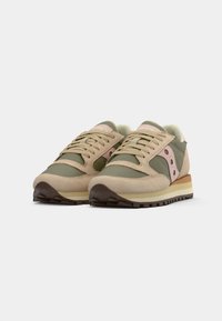 Light beige and olive green running shoes with pink accents, suede and textile materials, padded collar, flat laces, and a textured rubber sole.