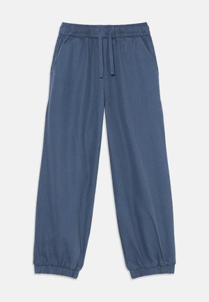 Blå joggebukser med elastisk midjebånd, snøring, sidelommer og elastiske mansjetter, lagt flatt på en hvit bakgrunn.