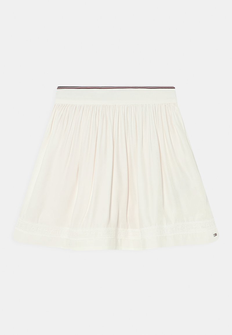 Falda blanca con plisados y cinturilla elástica, con finas franjas rojas y negras y un texto de marca sutil cerca del dobladillo.