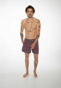 Shorts da bagno da uomo, tessuto viola scuro uniforme, vita elastica con cordoncino, tasche frontali, lunghezza fino al ginocchio, texture liscia, piedi nudi.