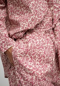 Set di pigiama con motivo floreale in tessuto leggero, caratterizzato da tonalità rosa e crema, con vita elastica e dettagli con bottoni.