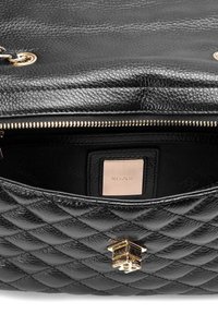 Borsa in pelle nera con motivo trapuntato, hardware dorato e chiusura con zip. L'interno presenta un rivestimento morbido con etichetta del logo.