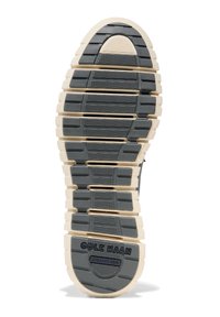 Grå och krämfärgad gummisul med ett strukturerat mönster, med en framträdande "Cole Haan Grand 360"-logotyp på hälen.