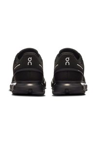 Schwarze Sportliche Schuhe mit einem Obermaterial aus Netzstoff, ausgestattet mit reflektierenden Akzenten und einer strukturierten Außensohle für besseren Halt. Das Markenlogo ist an der Ferse sichtbar.