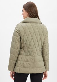 Gepolsterte Jacke in hellolivgrün, mit breitem Kragen, Rautenmuster und verlängerten Ärmeln; glatte Textur und taillierte Passform.
