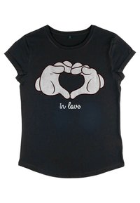Sort t-shirt med korte ærmer, der har et grafisk motiv af hænder, der danner en hjerteform, med sætningen "in love" i hvid nedenfor designet.