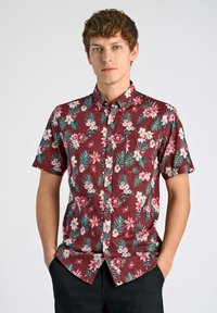 Korte mouwen burgundy shirt met tropisch bloemenpatroon in roze, wit en groen. Voorzien van een knoopsluiting aan de voorkant en één borstzak.