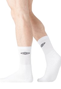Chaussettes en coton blanc, de type crew, avec une texture côtelée, ornées d'un logo en forme de diamant noir sur le côté. Matériau doux et légèrement épais.