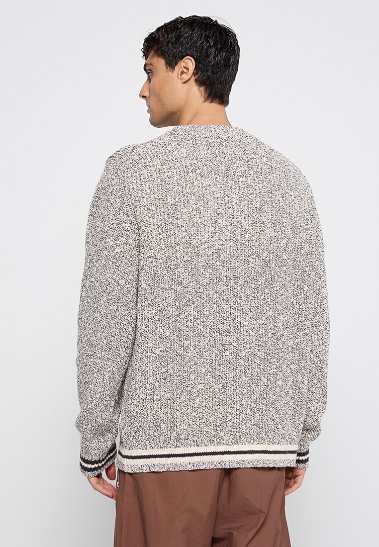 Grau-weißer Strickpullover mit einem strukturierten Muster, ausgestattet mit gerippten Bündchen und Saum in Schwarz und Creme. Rückansicht dargestellt.