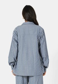 Gestreepte blauw-witte shirt met een ontspannen fit, voorzien van lange mouwen, een klassieke kraag en een rugdeel met een detail. Zacht, gestructureerd stof.