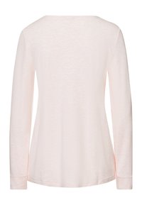 Vaaleanpunainen pitkähiha, joka on pehmeästä ja teksturoidusta kankaasta. Siinä on leveä kaula-aukko ja rento istuvuus, suunniteltu mukavuutta varten.