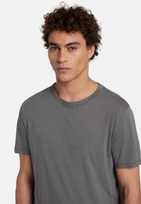 T-shirt grigio a maniche corte con scollo rotondo e texture morbida. Design semplice senza motivi o accenti visibili.
