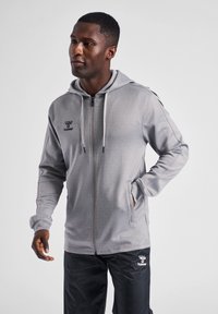 Grijze hoodie met rits van textuurstof, verstelbare trekkoordkap, en zijzakken, voorzien van een klein logo op de linkerborst.