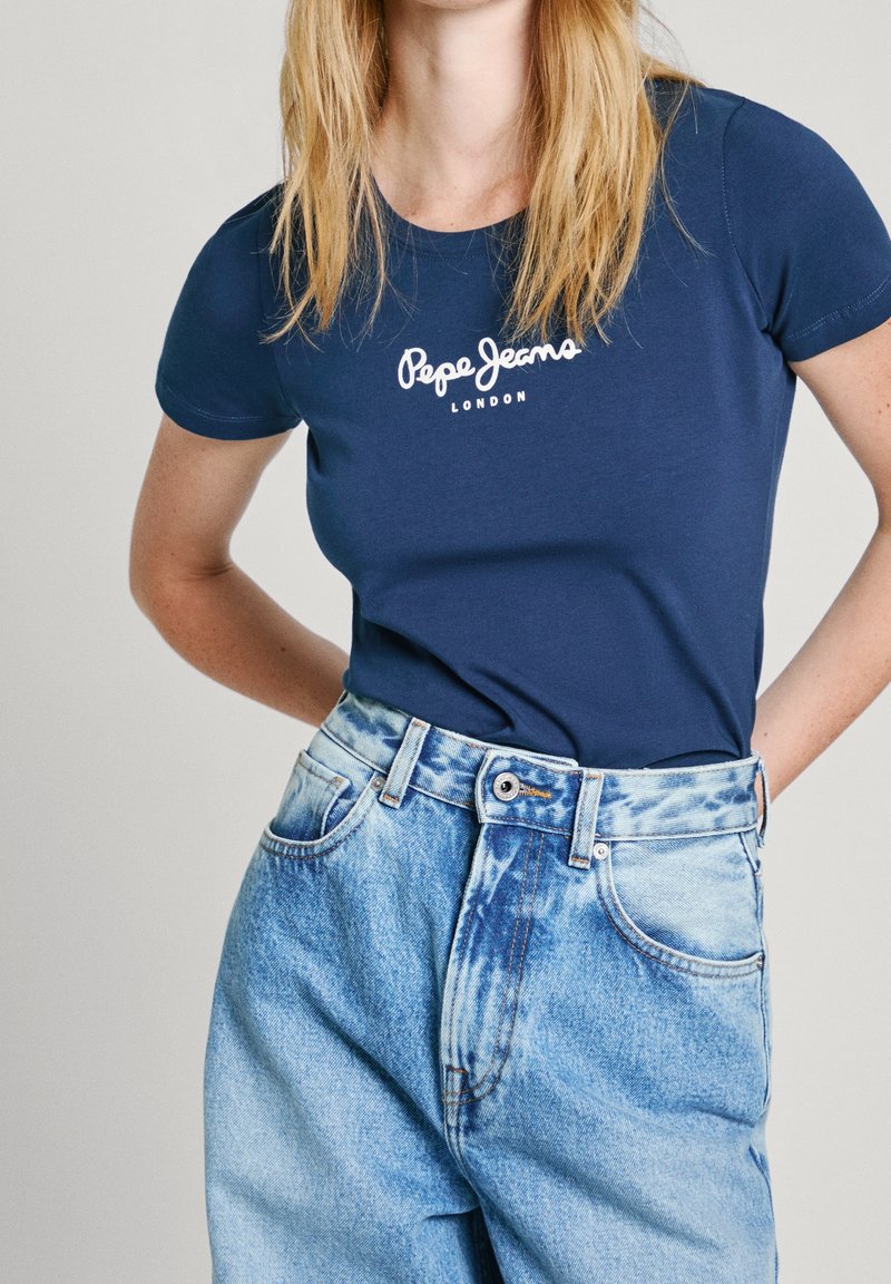 Laivastonsininen, lyhythihainen puuvillainen t-paita, jossa valkoinen "Pepe Jeans London" -logo. Yhdistetty vaaleansinisiin korkeavyötäröisiin farkkuihin.