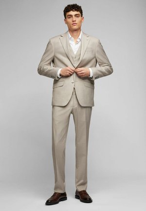 Beige three-piece suit with a slim fit, solid pattern, single-breasted jacket, notch lapels, and button details, complemented by brown shoes.