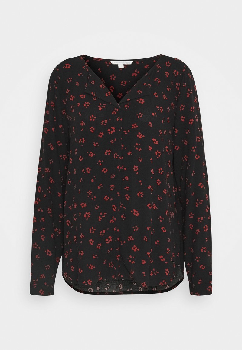 Blouse noire à manches longues avec petit motif floral rouge et col en V, présentée sur un fond blanc uni.