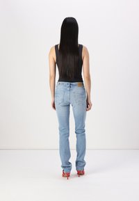 Svijetloplave traperice ravnog kroja, s pet džepova i smeškim kožnim logom na poleđini. Uparene s crnim topom bez rukava i crvenim potpeticama.