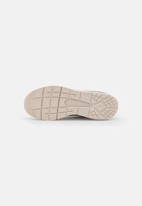 Sneaker outsole in light beige rubber with textured grip pattern and ridges for traction. Rounded toe and slightly raised heel design.