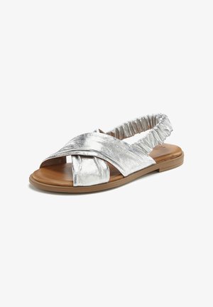 Silver metallic slide sandal with twisted front design and elastic back strap; flat sole with brown accents; smooth texture.