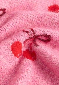 Strickstoff in Pink mit glatter Textur, der rote Kirschmuster und dunklere Akzente aufweist. Der Hintergrund zeigt ein weiches, flauschiges Erscheinungsbild.