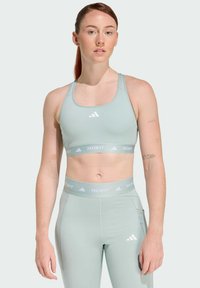 Jasnozielony sportowy top typu crop oraz dopasowane legginsy, wykonane z elastycznego materiału. Posiadają szeroką taśmę Techfit oraz charakterystyczne logo z trzema paskami.