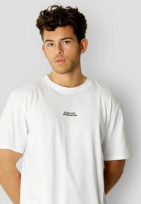 Hvit T-skjorte med korte ermer som har en svart trykket logo "CLEAN CUT COPENHAGEN" på brystet, laget av mykt bomullsmateriale.