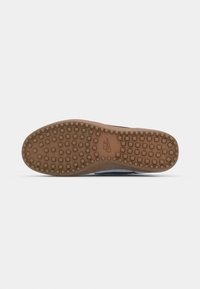 Semelle de chaussure avec bande de roulement en caoutchouc marron comportant des crampons carrés et le logo Nike embossé au centre.