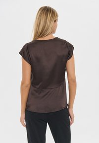 Smeđa satenasta bluzica s kratkim rukavima, okruglim izrezom i slobodnim krojem, s glatkom teksturom i minimalističkim dizajnom.