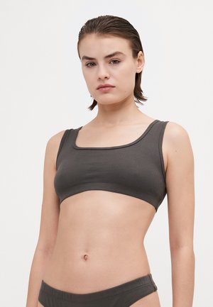 Donkergrijze geribbelde bralette met vierkante halslijn en brede bandjes, die zorgt voor een zachte textuur en een naadloos ontwerp. Gecombineerd met bijpassende onderkleding.