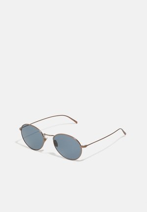 Oval sunglasses with blue tinted lenses. Thin metal brown frames with a minimalist design. Adjustable nose pads for comfort.