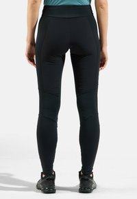 Leggings de sport noirs avec une texture lisse et extensible. Dotés d'une taille haute et d'un design ajusté, avec des coutures accentuées au niveau des cuisses.