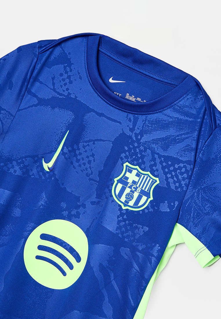 Maillot de football FC Barcelone bleu avec logo Nike vert fluo, blason et logo du sponsor Spotify, arborant un motif abstrait subtil.