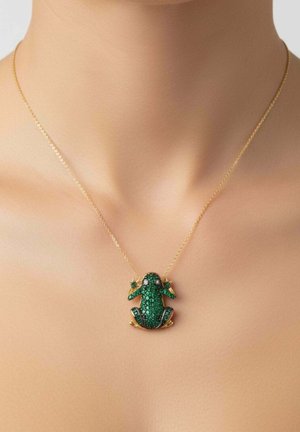 Goldkette mit einem grünen, mit Edelsteinen besetzten Froschanhänger, der in der Mitte eines nackten Halses und Schlüsselbeinbereichs liegt.