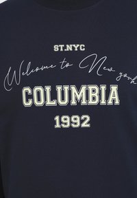Sudadera azul marino con texto gráfico. Presenta "Bienvenido a Nueva York", "COLUMBIA" y "1992" en fuentes de color claro en contraste.