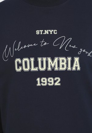Marineblauwe sweatshirt met grafische tekst. Bevat "Welcome to New York," "COLUMBIA," en "1992" in contrasterende lichtere lettertypen.
