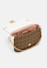 Sac à main à motif marron avec un rabat en cuir blanc, quincaillerie dorée et une bandoulière en chaîne. Intérieur doublé de tissu neutre avec une poche zippée.