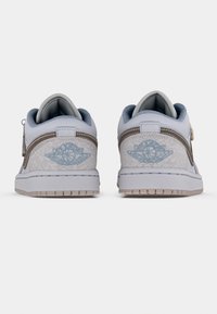 Madalad tennised valges ja hallis värvitoonis, millel on tekstuurne muster, sinised aktsendid ja kontsapingil logo. Viimistletud kummisest taldiga.