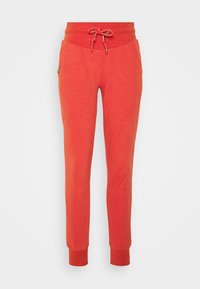 Červené tepláky vyrobené z měkkého materiálu, s elastickým pasem a šňůrkou na stažení a zúženými manžetami u kotníků.