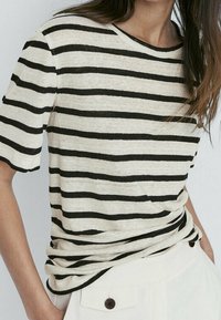 Krämfärgad t-shirt med svarta horisontella ränder, korta ärmar och avslappnad passform. Mjukt material med en avslappnad, strukturerad look.