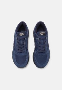Navy blue sneakers featuring a mix of suede and mesh materials, with round laces, cushioned insoles, and a textured rubber outsole.