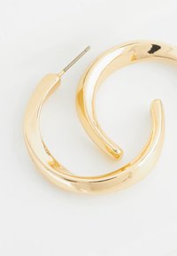 Golden hoop earrings with a smooth, shiny surface and curved design. Each earring features a slender, pointed post for secure wear.