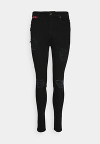 Jeans ajustados negros con detalles rasgados en las rodillas, fabricados en denim, con cierre de botón y una etiqueta con acentos rojos en la cintura.