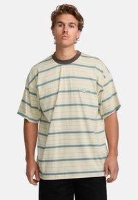 Camiseta de manga corta color crema con rayas azules horizontales, cuello redondo marrón y un pequeño logo en la parte izquierda del pecho.