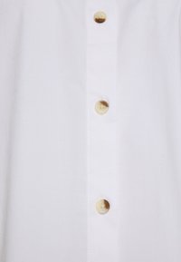Witte button-up shirt met een rechte kraag, vijf ronde lichtgele knopen en een gladde, niet-textuurstof.